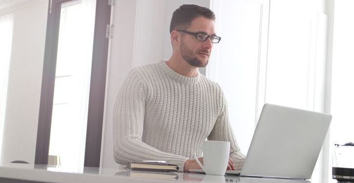 An adult professional works on his laptop at home.