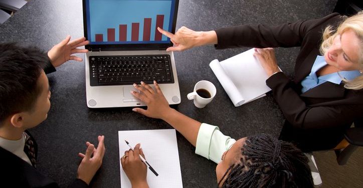 A business team looks at business growth on a computer.