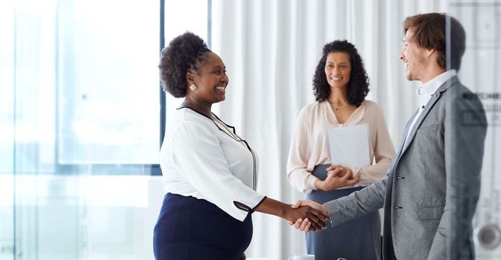 A hiring manager shakes the hand of a new employee.