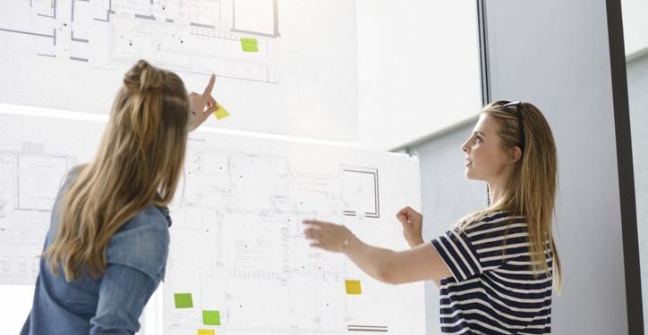 Two businesswomen plan out a project.