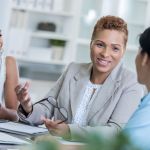 Organizational Leadership depicted as businesswoman discusses a project with her team.