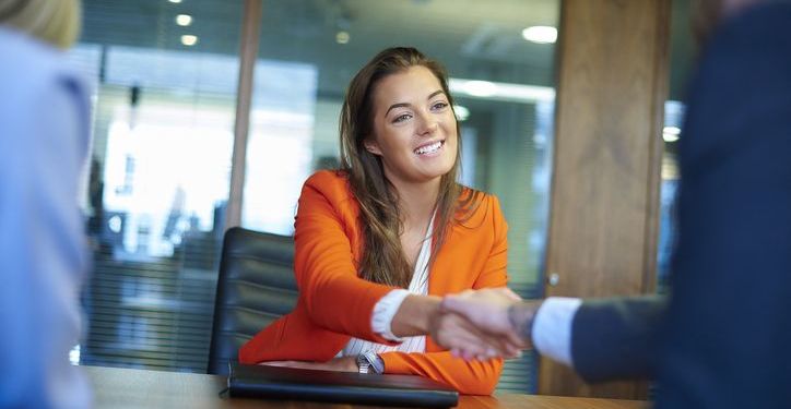 Confident professional shakes hands with hiring manager in a job interview