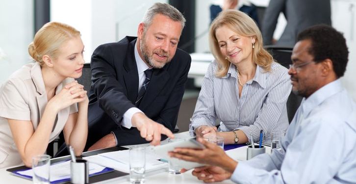 Team leader discusses a project with their team in an office.