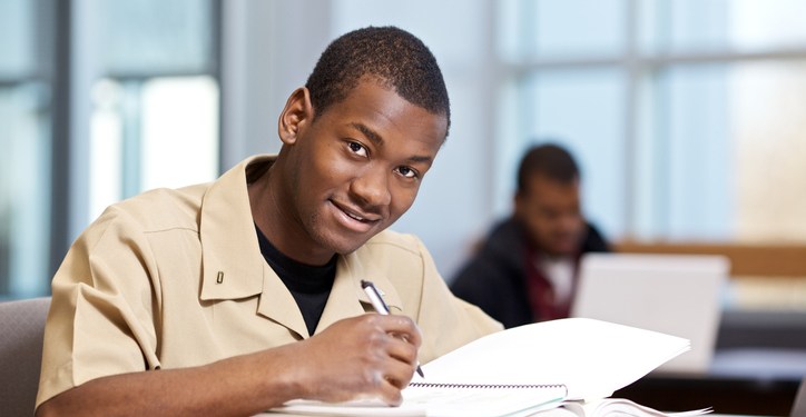 Military student in beige uniform smiling while studying