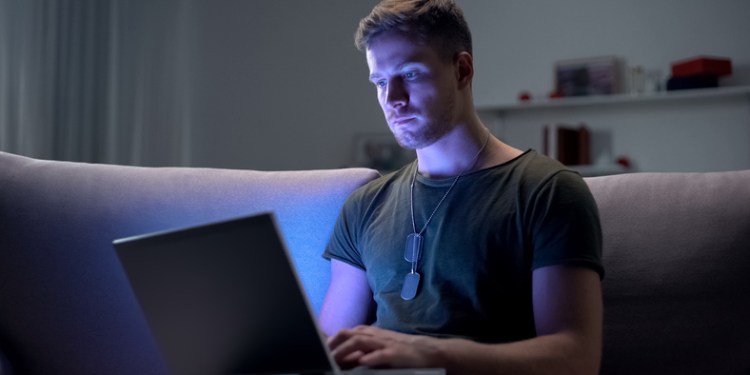 Military servicemember using laptop at home