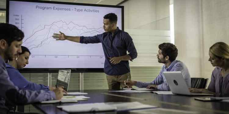 African American businessman presenting a data visualization in front of colleagues in an office.